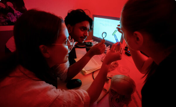 Players working with lab props in the Zombie Lab escape room at Fox in a Box Adelaide, surrounded by biohazard equipment and eerie lighting.