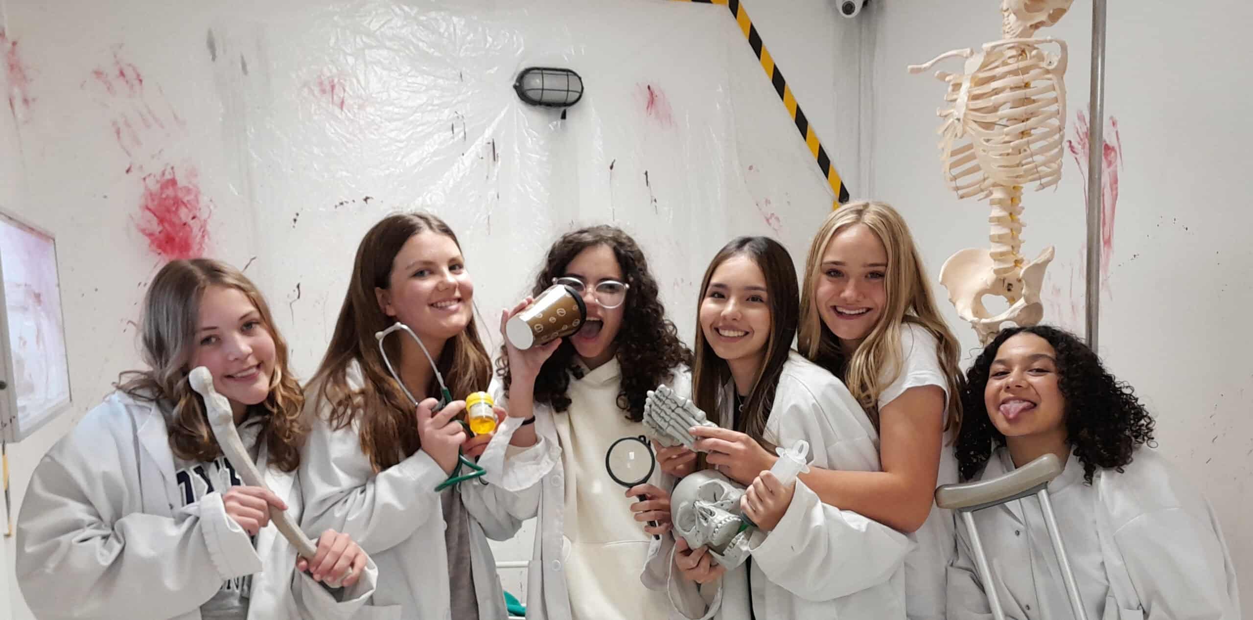 A group of girls in lab coats posing for a photo.